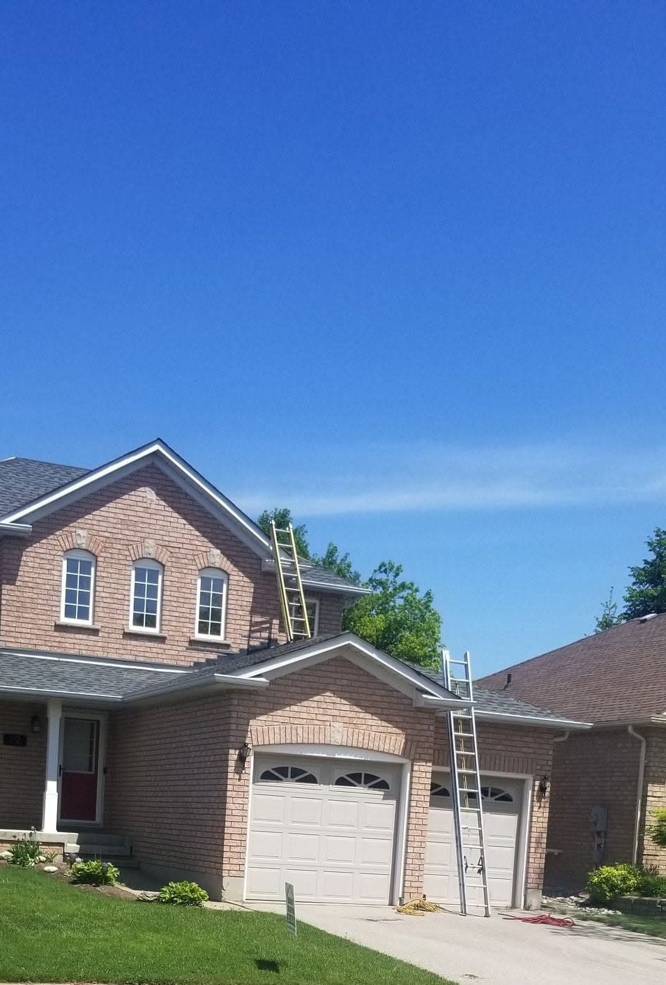 Ladders set up against a two storey brick house on a Brian's Roofing job
