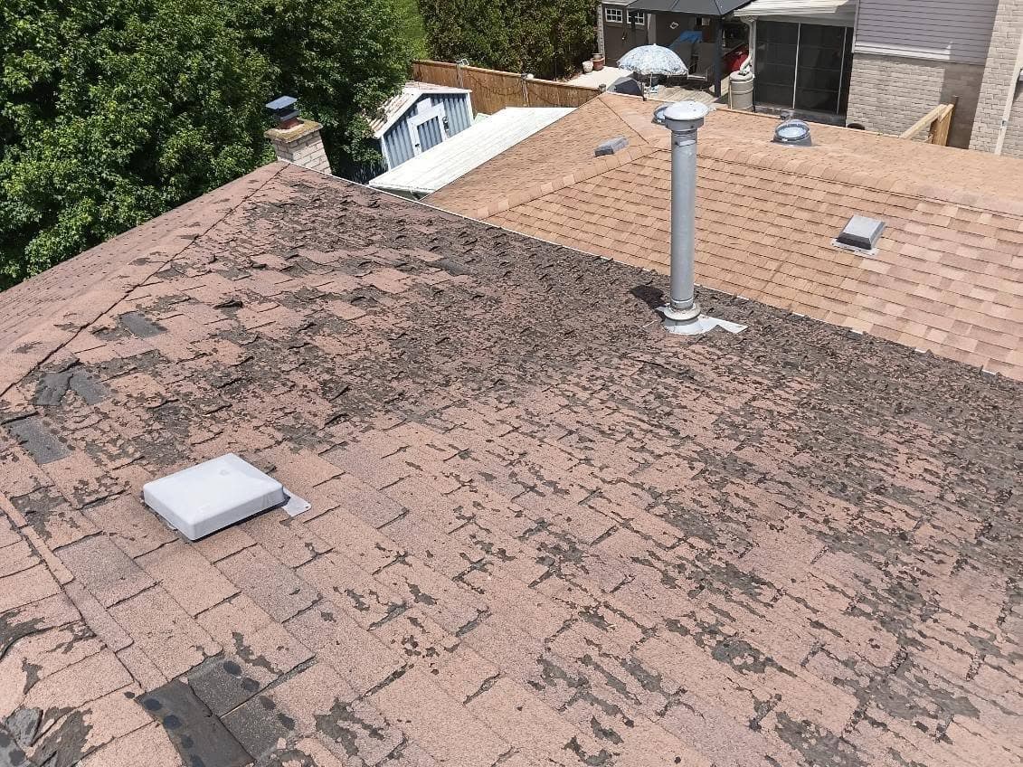 Worn, weathered shingles on a roof before tear off